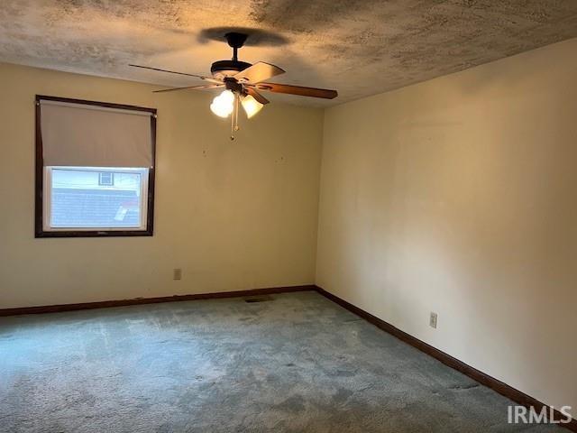 spare room with ceiling fan, a textured ceiling, and carpet floors