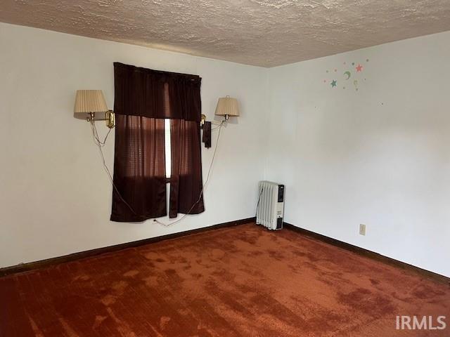 empty room with carpet floors, a textured ceiling, and radiator heating unit