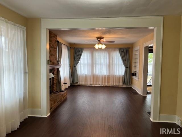 unfurnished living room with a fireplace, ceiling fan, and dark hardwood / wood-style flooring