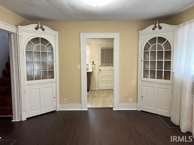 unfurnished dining area with dark wood-type flooring