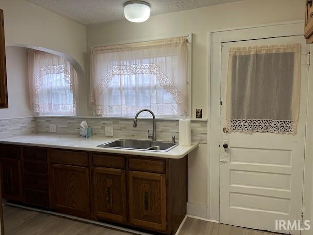 kitchen with tasteful backsplash, hardwood / wood-style floors, sink, and a textured ceiling