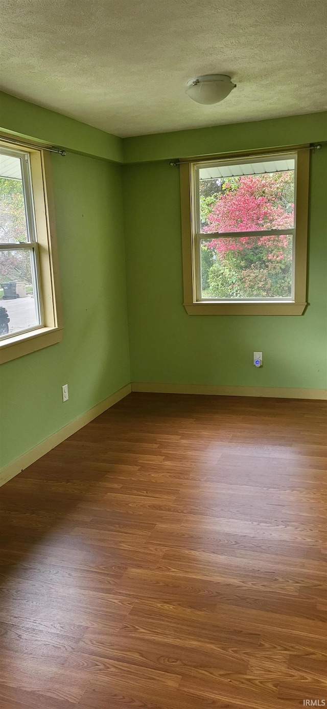 empty room with wood-type flooring and a textured ceiling