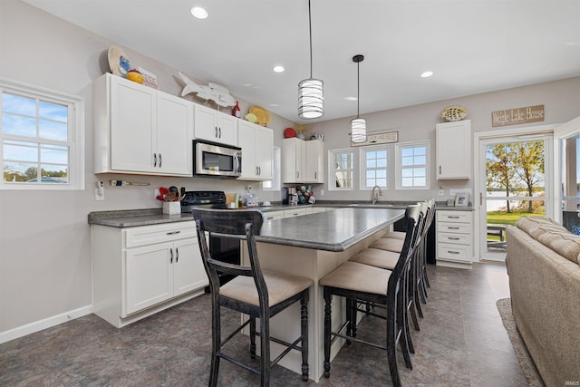 kitchen with a kitchen island, white cabinets, sink, a breakfast bar area, and decorative light fixtures