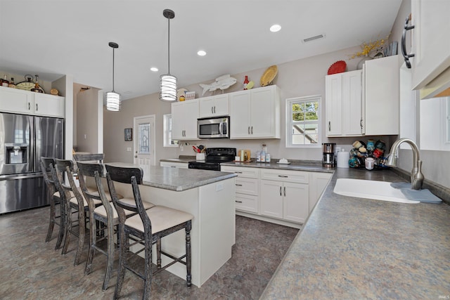 kitchen with a breakfast bar area, sink, stainless steel appliances, white cabinets, and a center island