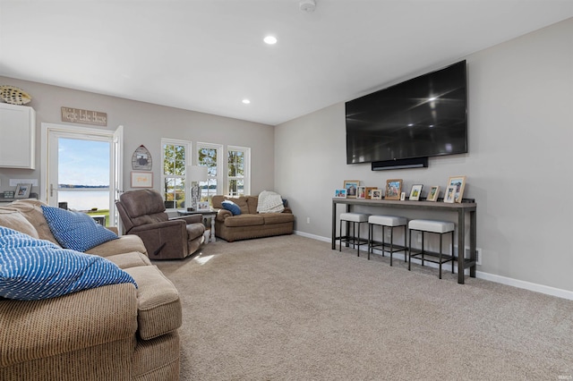 living room featuring light colored carpet, plenty of natural light, and a water view