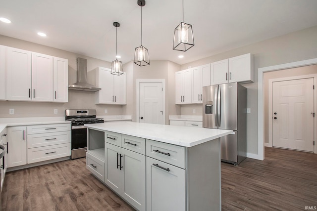 kitchen featuring appliances with stainless steel finishes, pendant lighting, wall chimney exhaust hood, and white cabinets