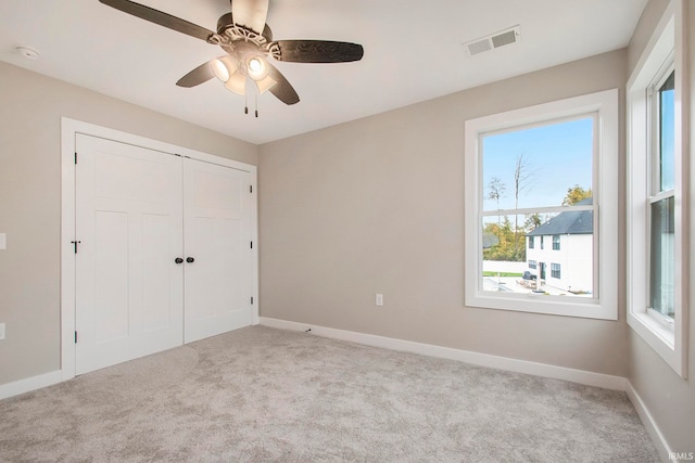 unfurnished bedroom with a closet, light carpet, and ceiling fan