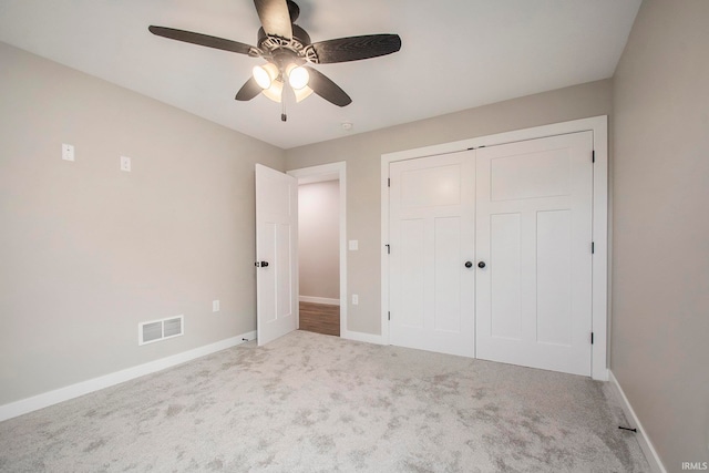 unfurnished bedroom with ceiling fan, light colored carpet, and a closet