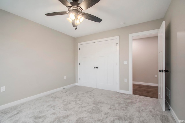 unfurnished bedroom with a closet, light colored carpet, and ceiling fan