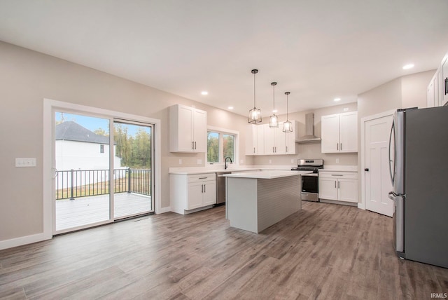 kitchen featuring a wealth of natural light, stainless steel appliances, wall chimney exhaust hood, and a center island