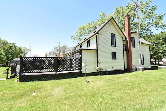 rear view of property with a yard, a wooden deck, and central air condition unit