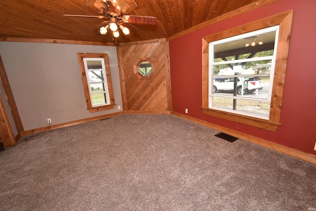 carpeted empty room featuring wood walls, wooden ceiling, lofted ceiling, and ceiling fan