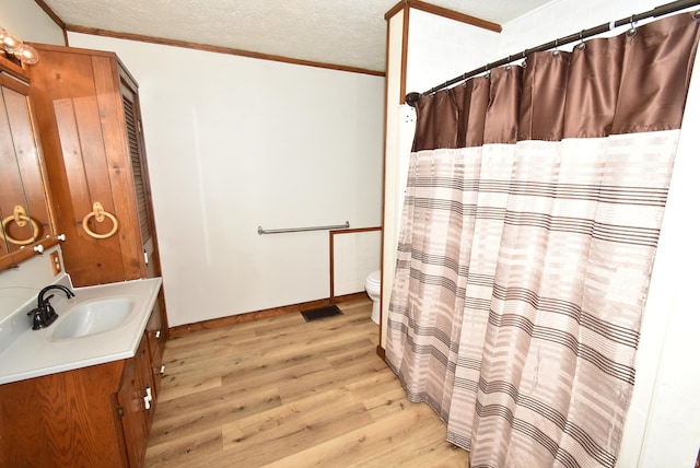 bathroom with vanity, toilet, a textured ceiling, walk in shower, and hardwood / wood-style floors