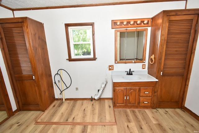 bathroom featuring ornamental molding, vanity, wood-type flooring, and a textured ceiling