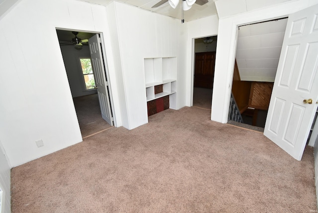 unfurnished bedroom featuring wood walls, carpet, and ceiling fan