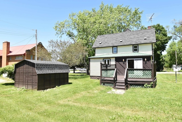 rear view of property featuring a deck, a lawn, and a shed