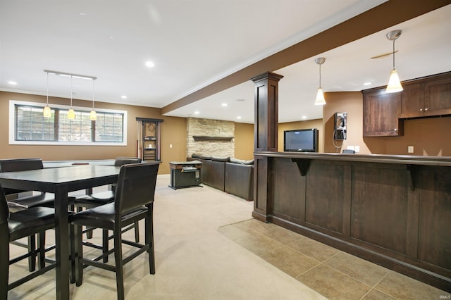 kitchen featuring ornate columns, crown molding, a breakfast bar, light carpet, and decorative light fixtures