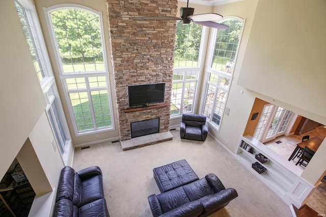 living room with carpet floors, a high ceiling, a wealth of natural light, and a stone fireplace