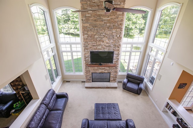 carpeted living room with a high ceiling, a healthy amount of sunlight, and a fireplace