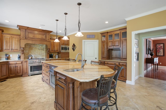 kitchen with crown molding, sink, stainless steel appliances, light stone countertops, and an island with sink