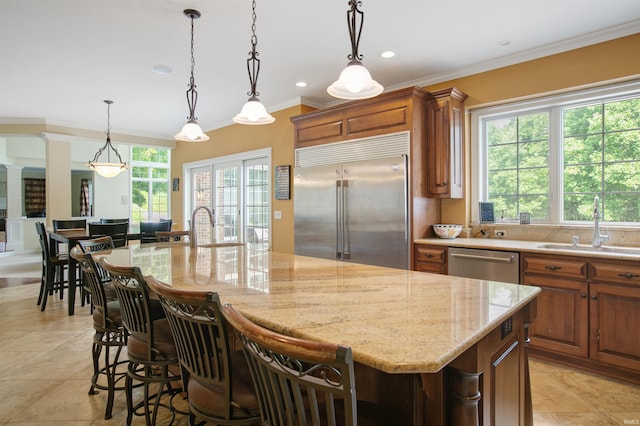 kitchen featuring appliances with stainless steel finishes, hanging light fixtures, plenty of natural light, and a kitchen island