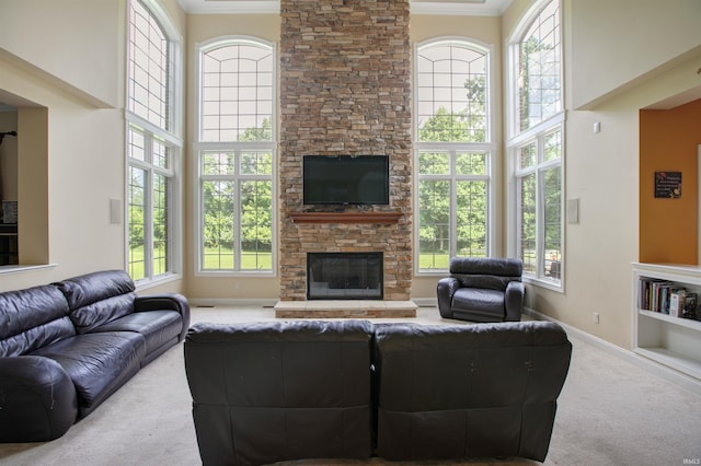 carpeted living room featuring a fireplace, crown molding, and a wealth of natural light