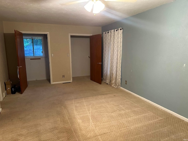 unfurnished bedroom with light carpet, a textured ceiling, and ceiling fan