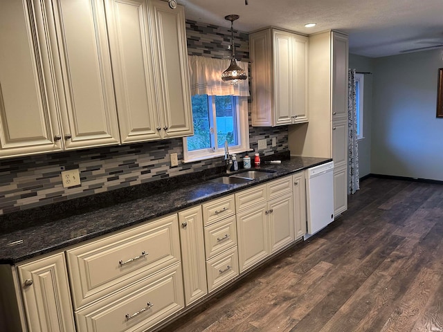 kitchen with dark hardwood / wood-style flooring, dark stone counters, dishwasher, pendant lighting, and sink