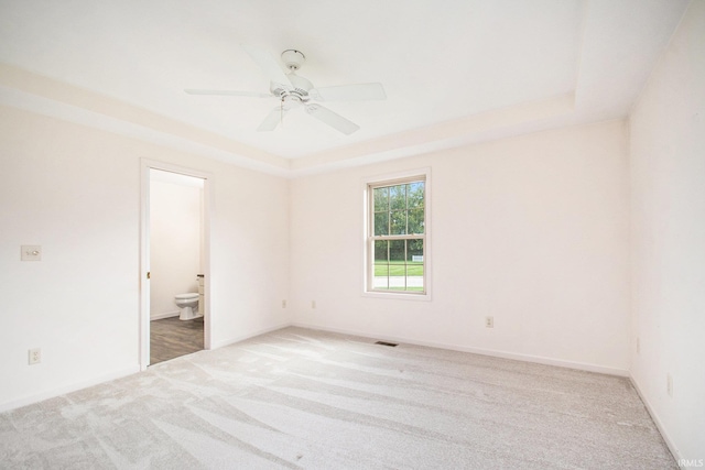 carpeted empty room featuring ceiling fan and a raised ceiling