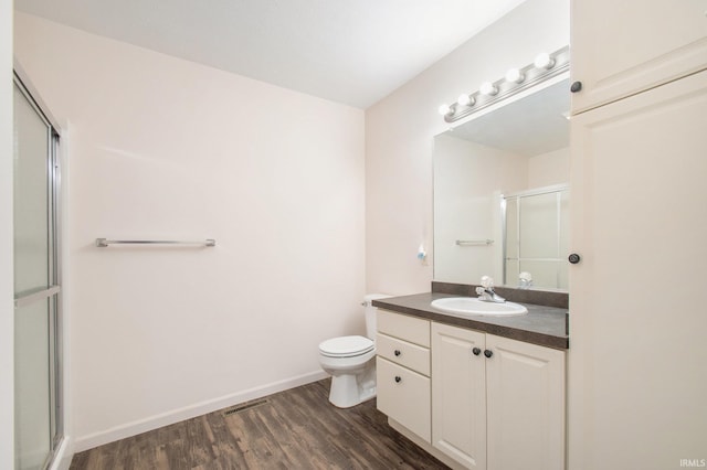 bathroom with vanity, hardwood / wood-style flooring, toilet, and an enclosed shower