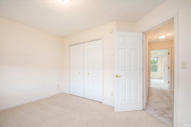 unfurnished bedroom with a closet and light colored carpet