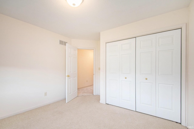 unfurnished bedroom with a closet and light carpet