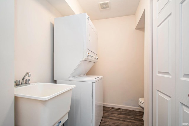 laundry area featuring sink, stacked washer and dryer, and dark hardwood / wood-style floors