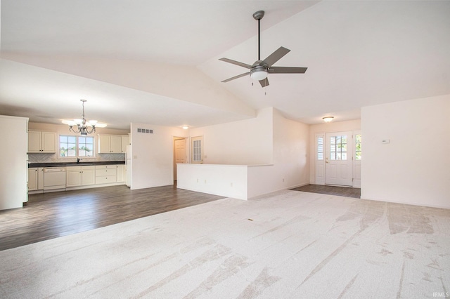 unfurnished living room featuring lofted ceiling, plenty of natural light, ceiling fan with notable chandelier, and hardwood / wood-style floors