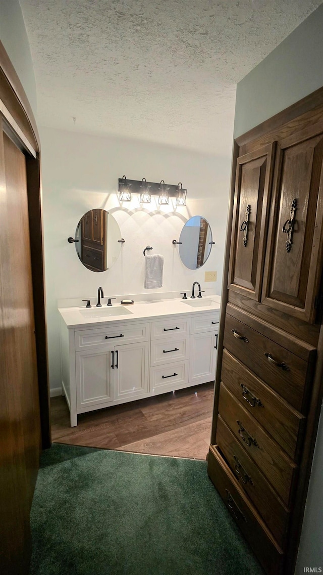 bathroom featuring vanity, wood-type flooring, and a textured ceiling