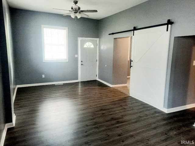 entrance foyer featuring dark wood-type flooring, a barn door, and ceiling fan