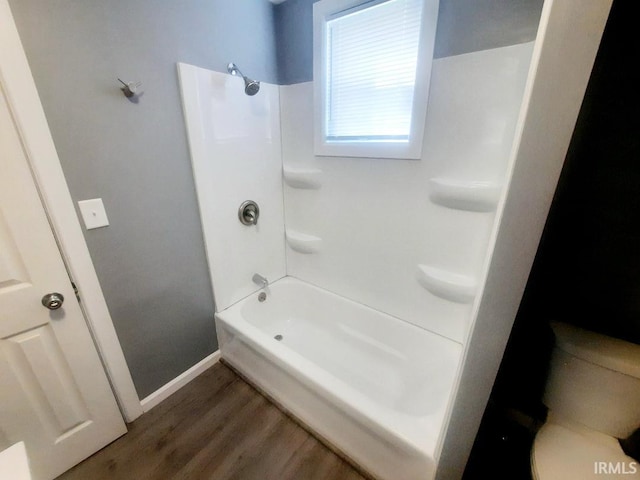 bathroom with toilet,  shower combination, and hardwood / wood-style floors