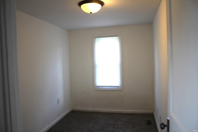 spare room featuring dark carpet