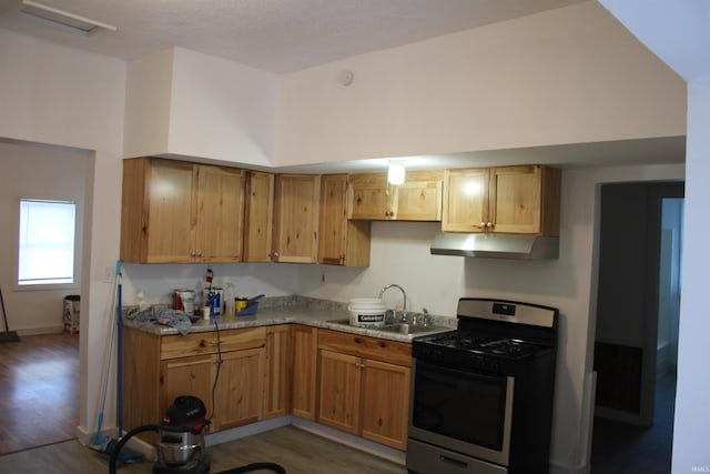 kitchen featuring stainless steel gas stove, light stone countertops, sink, and dark hardwood / wood-style flooring