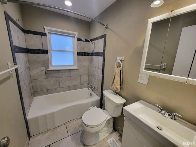 full bathroom with tile patterned flooring, tiled shower / bath combo, vanity, and toilet