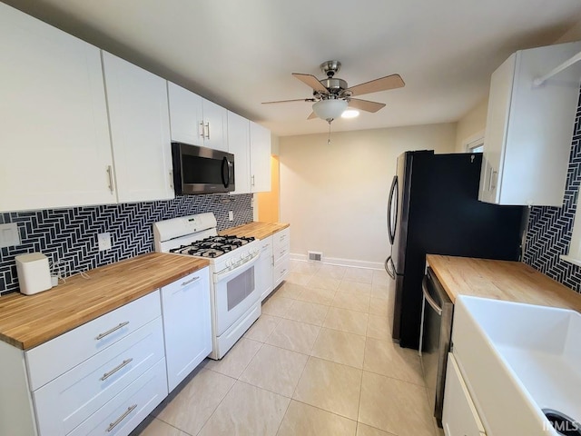 kitchen featuring ceiling fan, tasteful backsplash, white cabinetry, appliances with stainless steel finishes, and wood counters