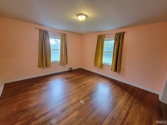 spare room featuring plenty of natural light and dark hardwood / wood-style flooring