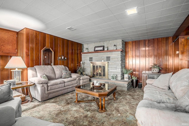 carpeted living room featuring a fireplace and wood walls