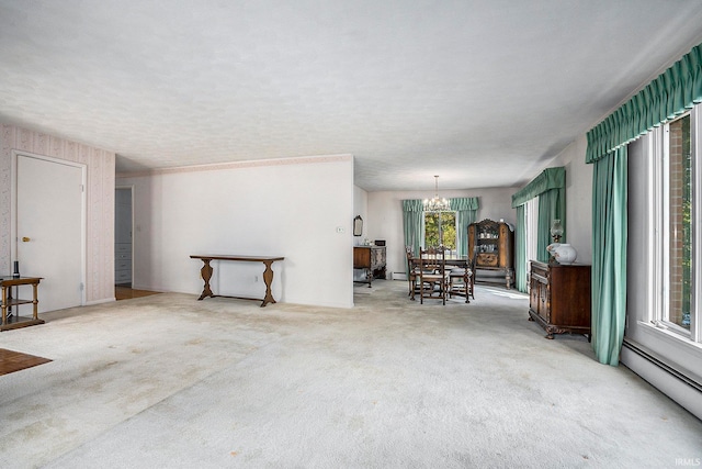 carpeted living room featuring a healthy amount of sunlight, a textured ceiling, an inviting chandelier, and baseboard heating