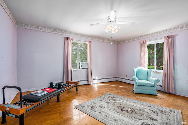 living area with cooling unit, hardwood / wood-style flooring, baseboard heating, and ceiling fan