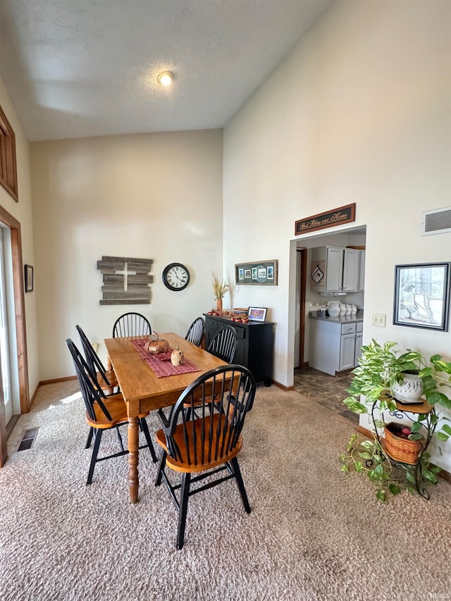 dining space featuring light carpet, high vaulted ceiling, and a textured ceiling