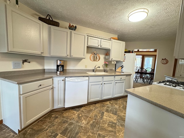 kitchen featuring white appliances, sink, a textured ceiling, and white cabinetry