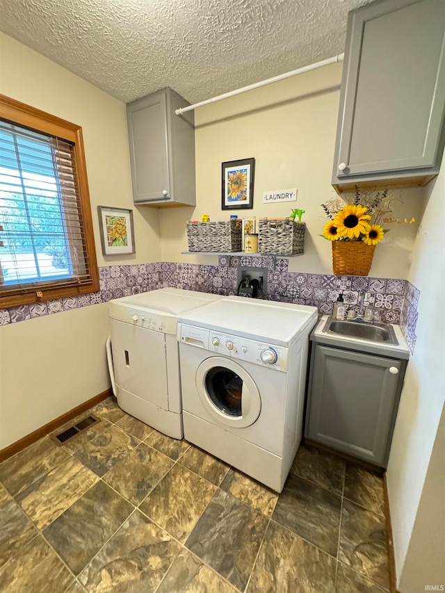 washroom with washing machine and clothes dryer, cabinets, a textured ceiling, and sink