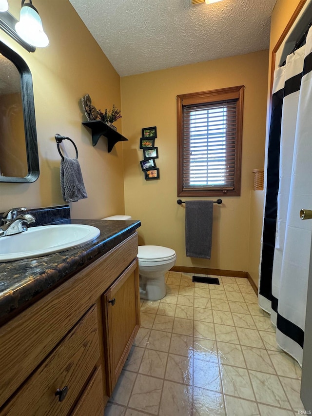 bathroom featuring toilet, vanity, and a textured ceiling