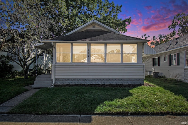 exterior space with a sunroom, a lawn, and central AC